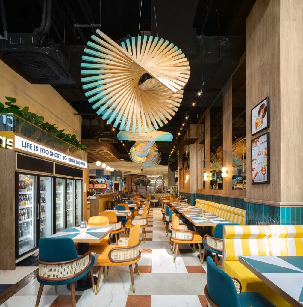 Interior of Beer Collection, a craft beer bar in Hua Hin, with striped banquette seating, lit display fridges and a pleated ceiling installation
