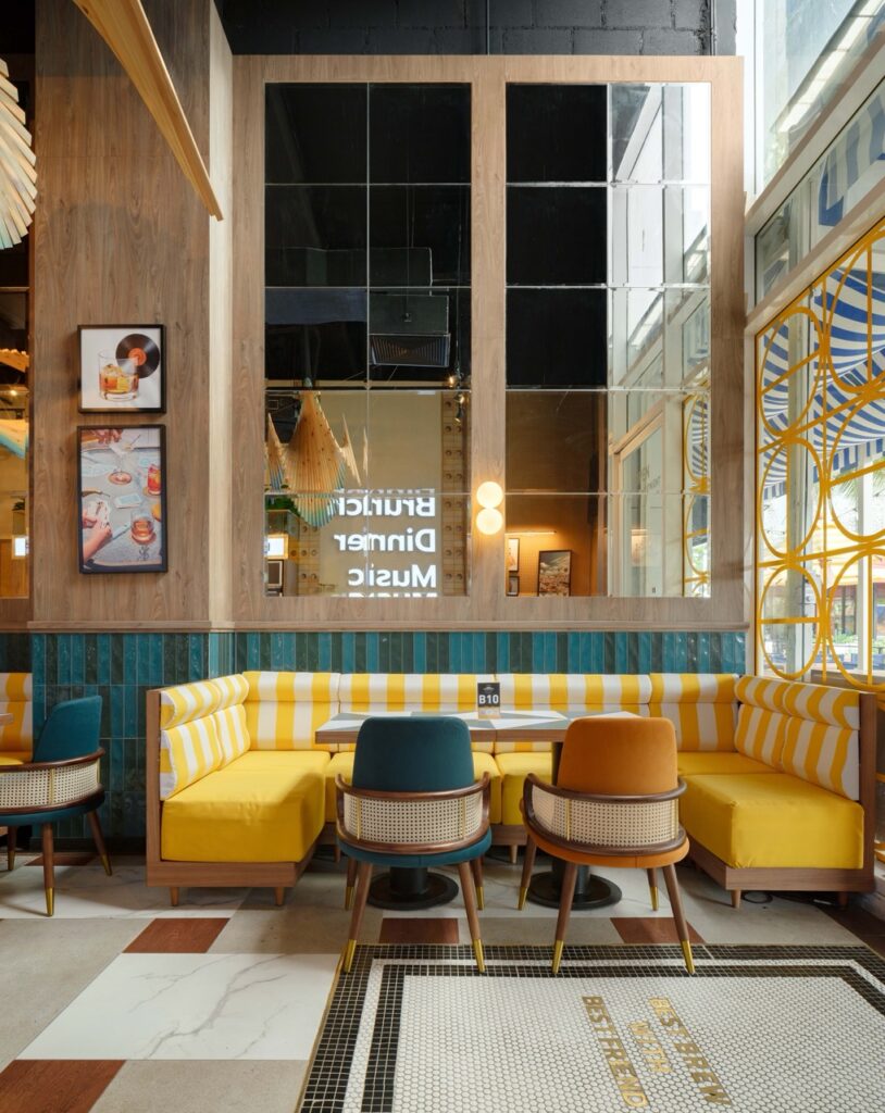 Booth seating in yellow stripe with caned tub chairs beside a full-height window