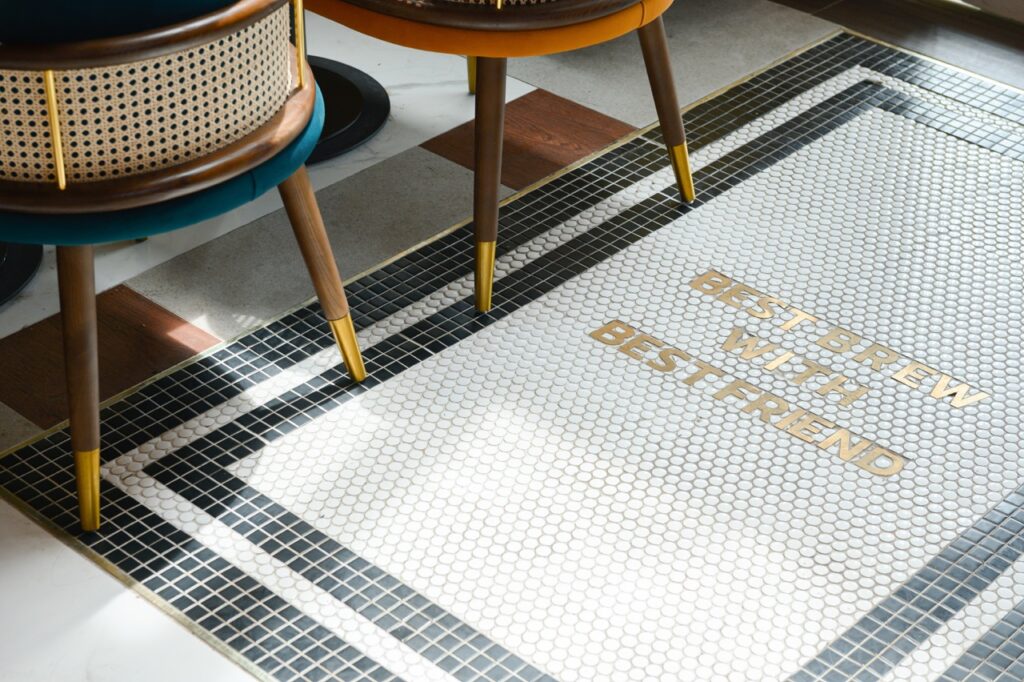 Brass lettering reading Best Beer With Best Friend inlaid into a mosaic tile floor