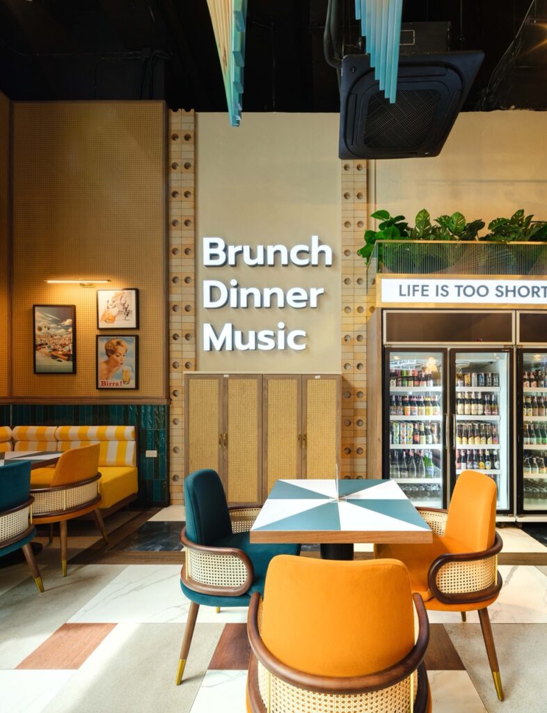 Wall graphic reading Brunch Dinner Music beside cane-fronted joinery and lit beer fridges