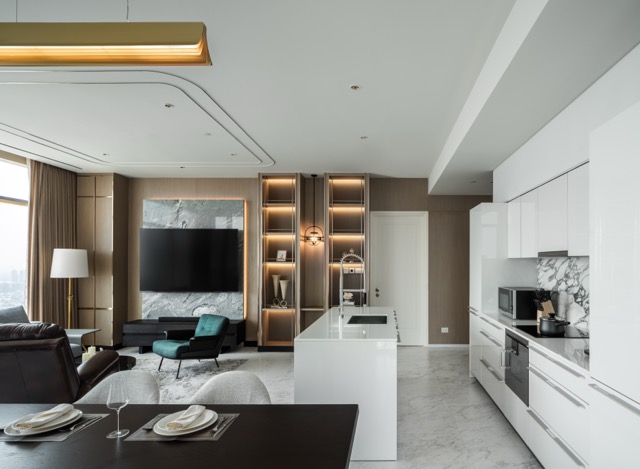 Open-plan living, dining and kitchen with white island and marble floor in an 80 sq m Bangkok apartment