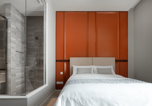 Second bedroom with burnt orange lacquered wardrobe wall and glass-walled shower