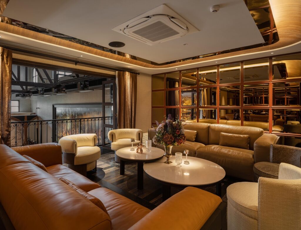 Mezzanine private lounge at Kilik Social Club with caramel leather sofas and mirrored panel wall