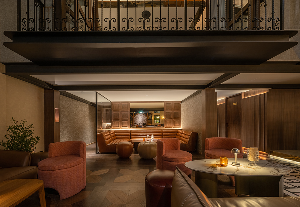 Quiet lounge beneath the mezzanine at Kilik Social Club with leather banquette and rose armchairs