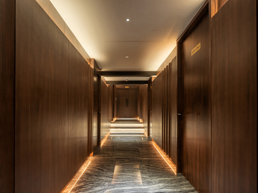 Timber-panelled corridor with recessed floor lighting at Kilik Social Club Bangkok