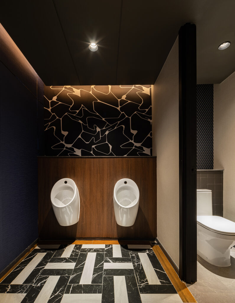 Washroom at Kilik Social Club with graphic black and white wallpaper, walnut panelling and marble basket-weave floor