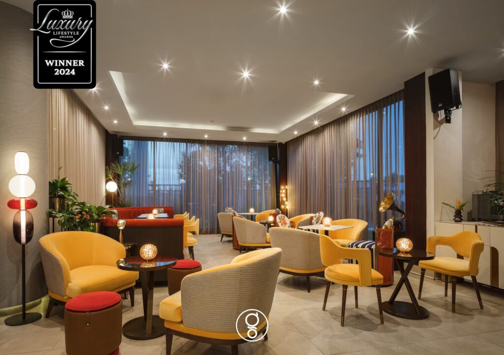 Topazio Bar lounge with saffron tub chairs, striped ottomans and a red banquette