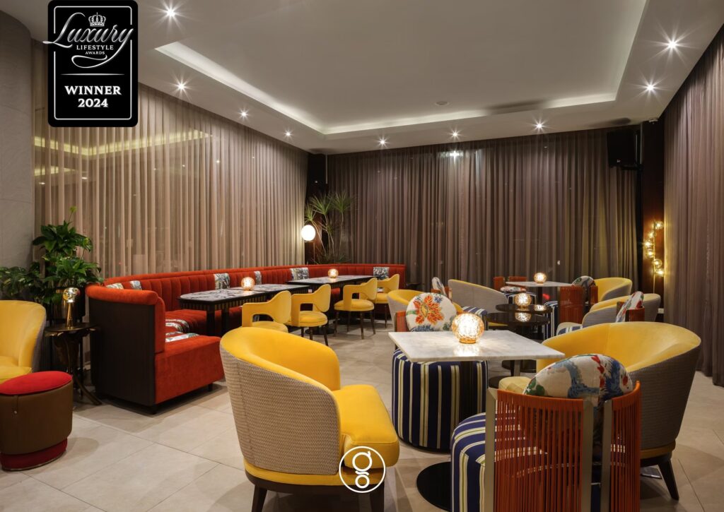 Curved terracotta banquette with marble tables and globe lighting at Topazio Bar