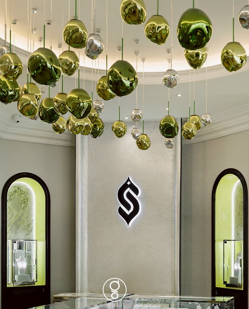 Ceiling detail of clustered green glass pendants above the Scintillion monogram, jewellery store interior design in Bangkok