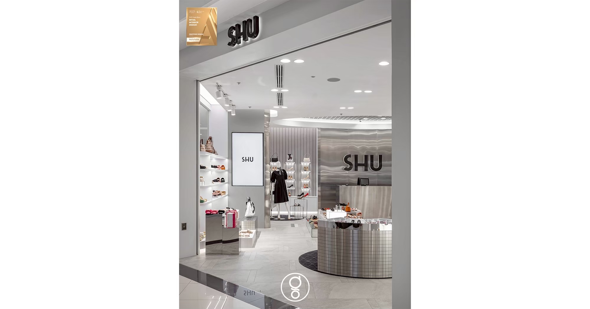 Entrance to the SHU store looking past a portrait display screen toward the stainless steel logo wall