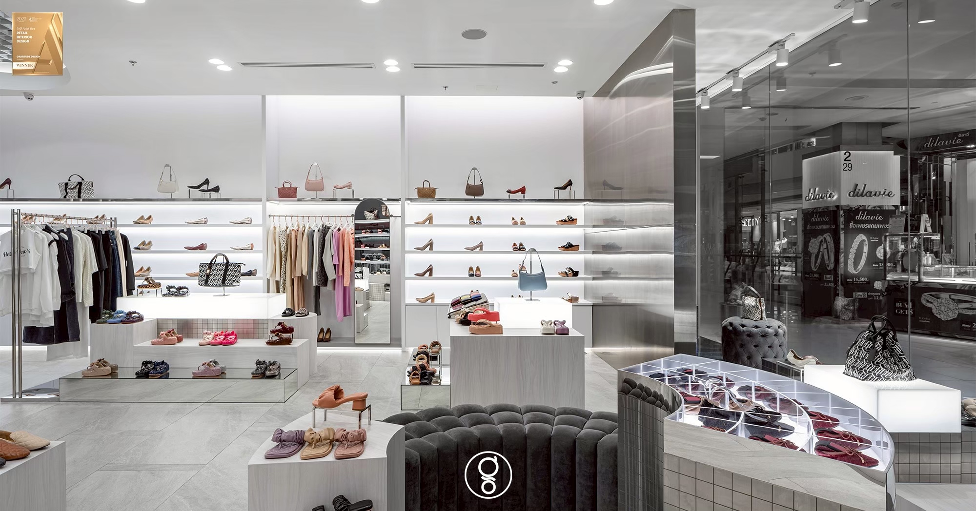 Curved mosaic display island with a lit acrylic grid top, velvet seating and backlit shelving beyond in the SHU store