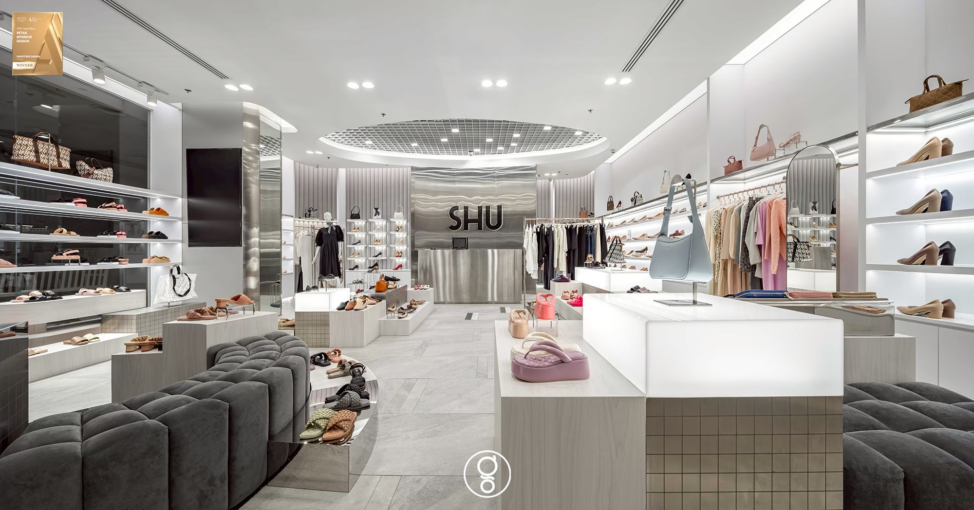 Open-cell metal grid disc set into the ceiling of the SHU store, lit from a cove and marking the centre of the shop floor