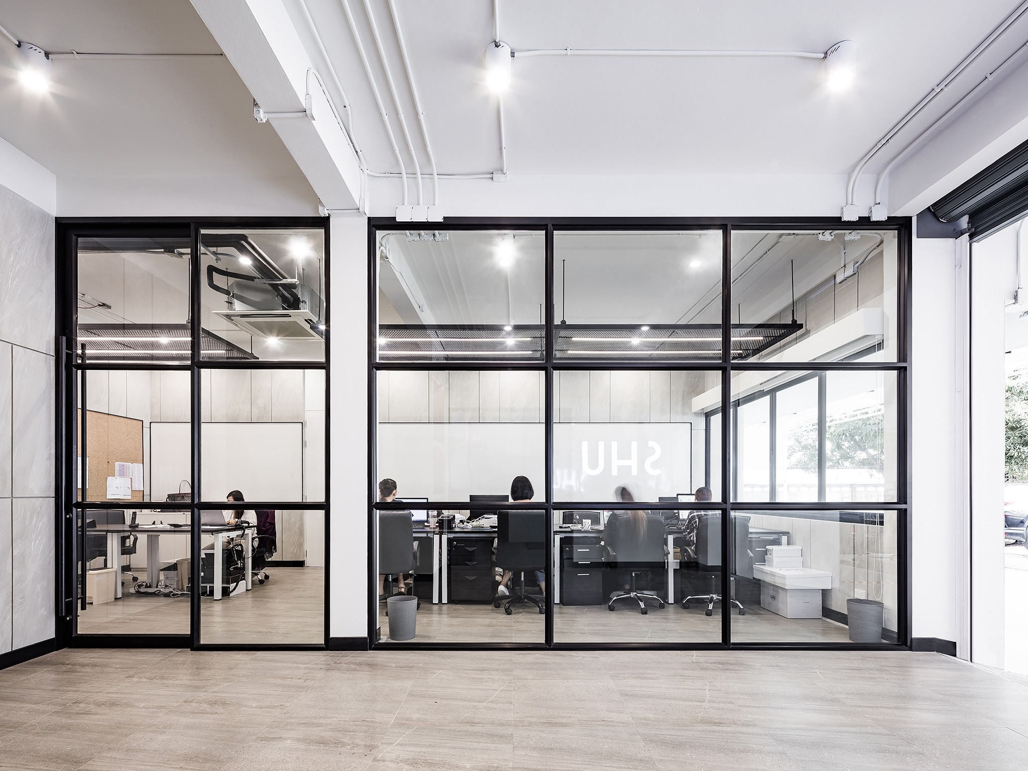 Head office interior design in Bangkok — black steel and glass partitions enclosing the SHU studio