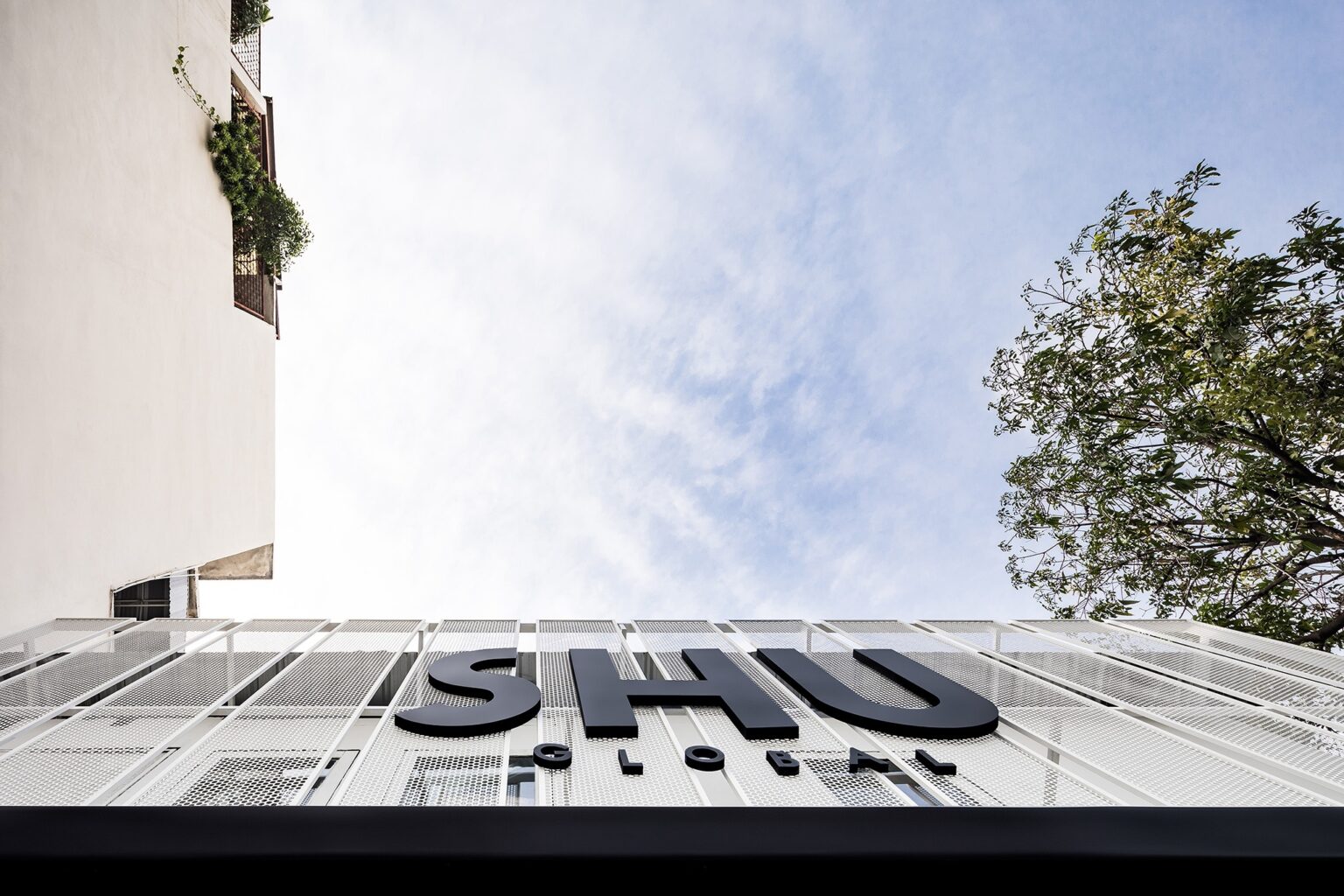 Flagship store facade in Bangkok — perforated screen seen from below against the sky