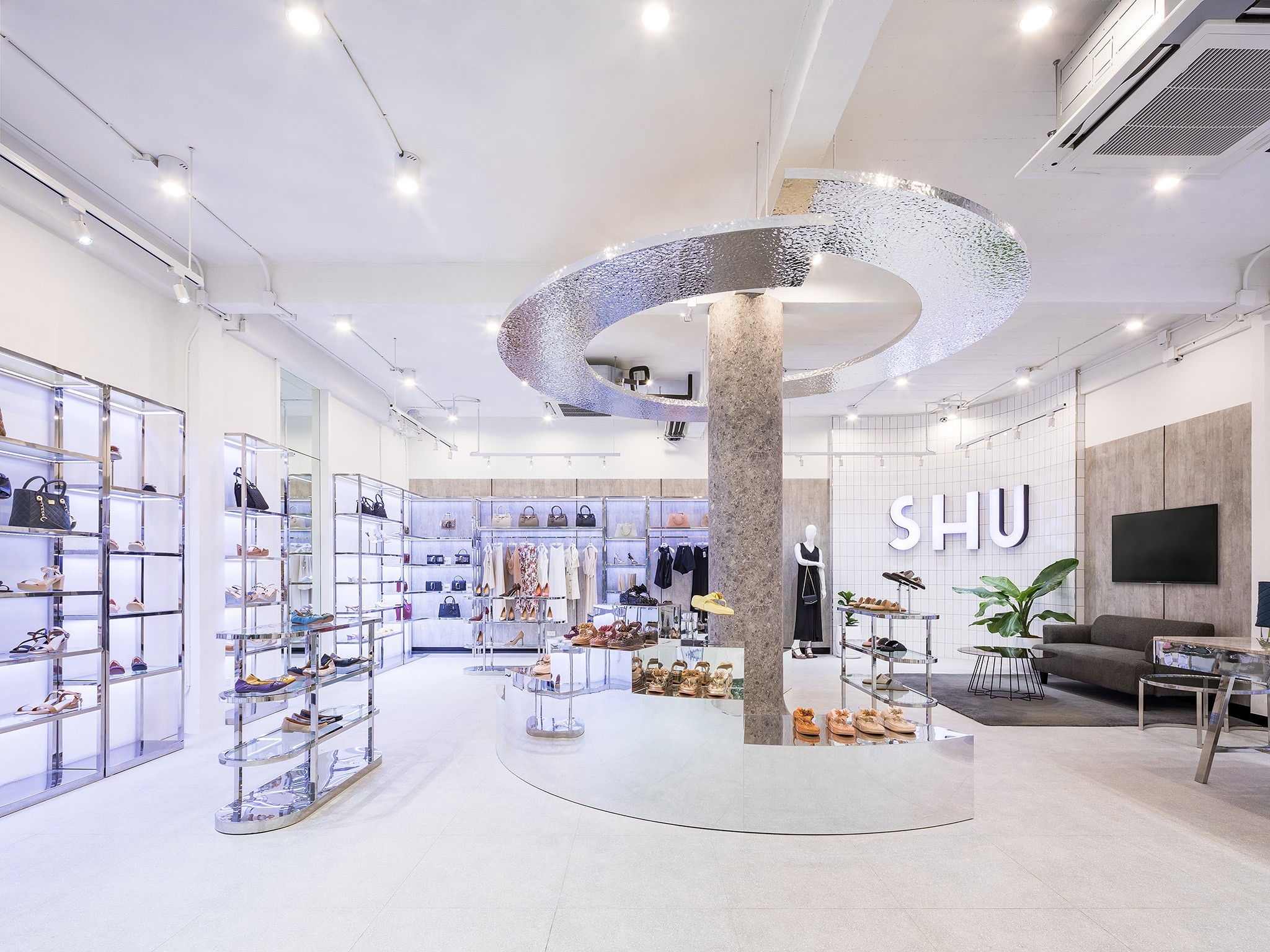 Shoe store interior design in Bangkok — hammered stainless ring ceiling above a mirrored display plinth