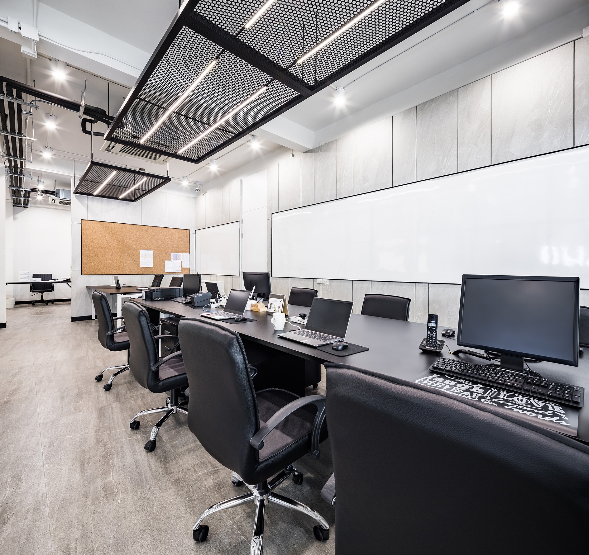 Head office interior design in Bangkok — perforated metal ceiling rafts with linear lighting over bench desking