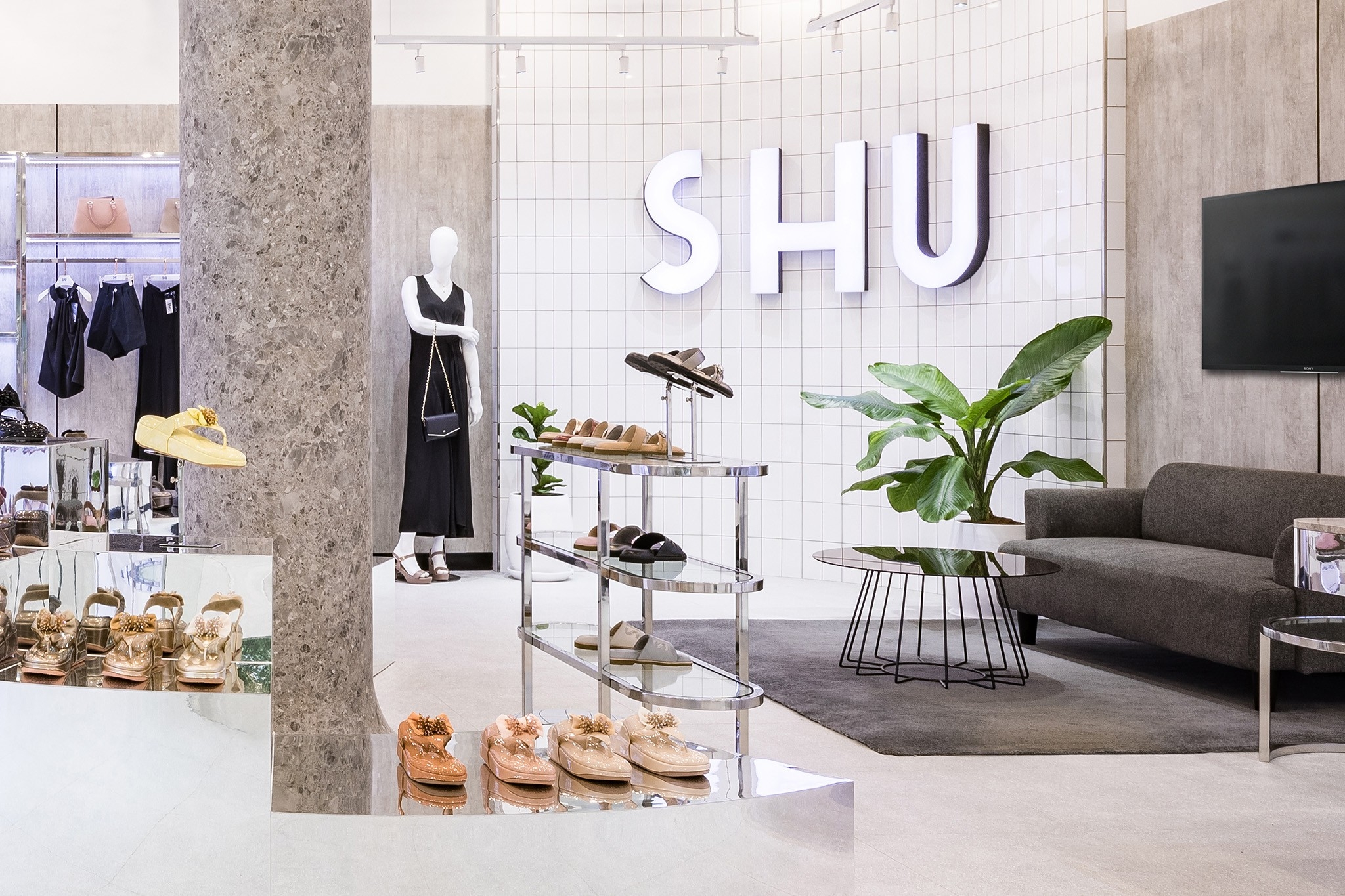 Flagship store interior design in Bangkok — lounge seating and planting below the backlit brand wall