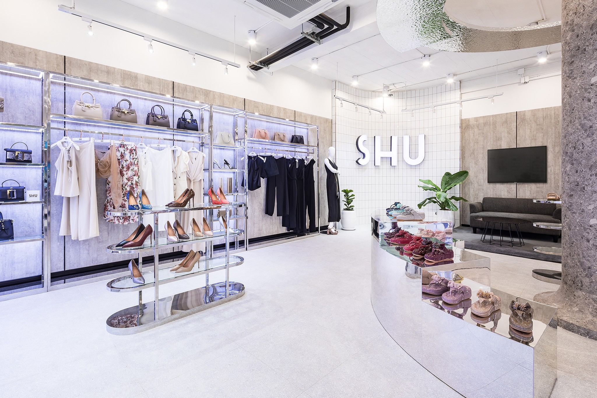 Retail interior design in Bangkok — apparel wall and mirrored plinth facing the backlit brand wall