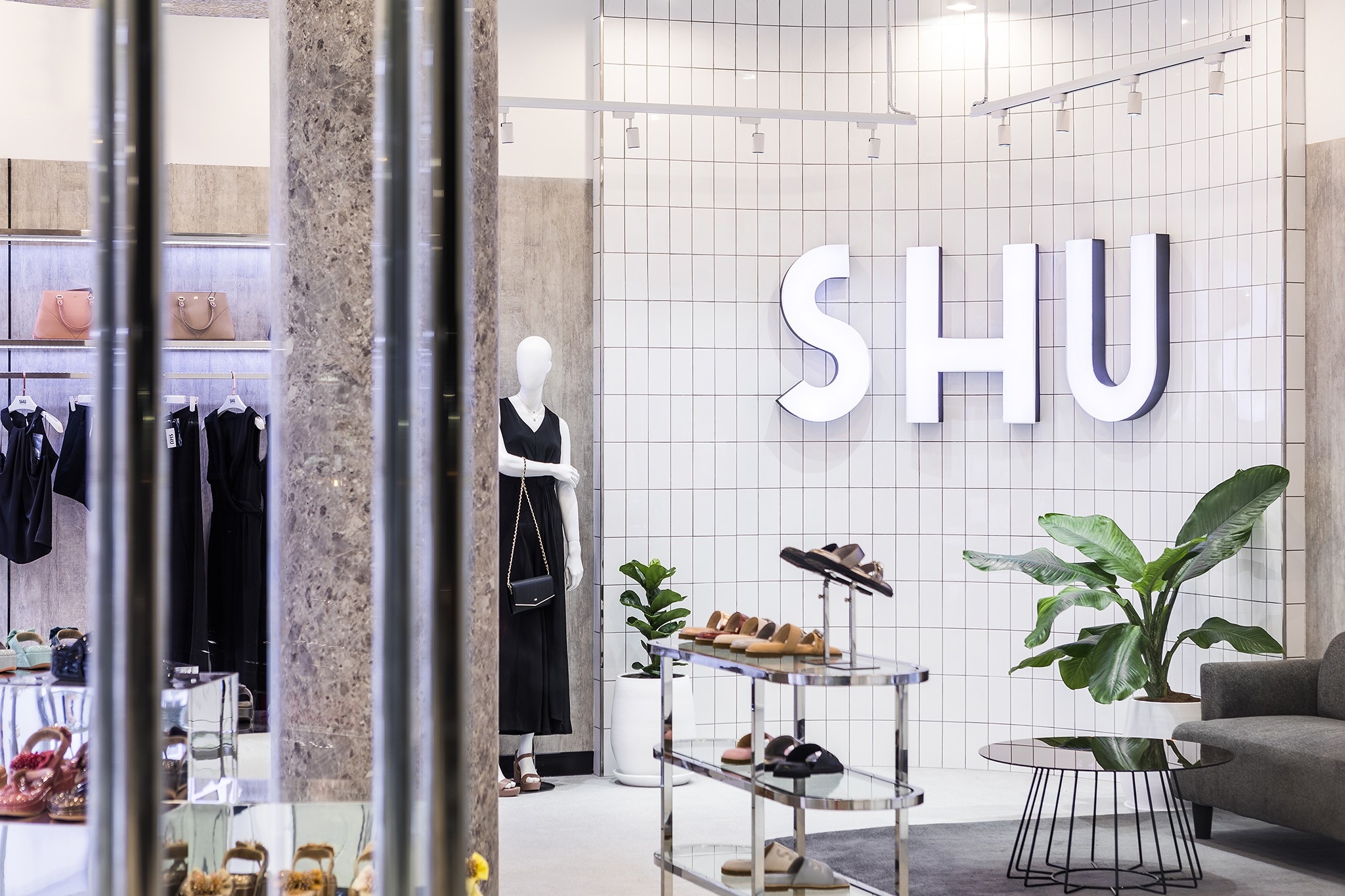 Flagship store interior design in Bangkok — halo-lit brand letters on a white grid tile wall