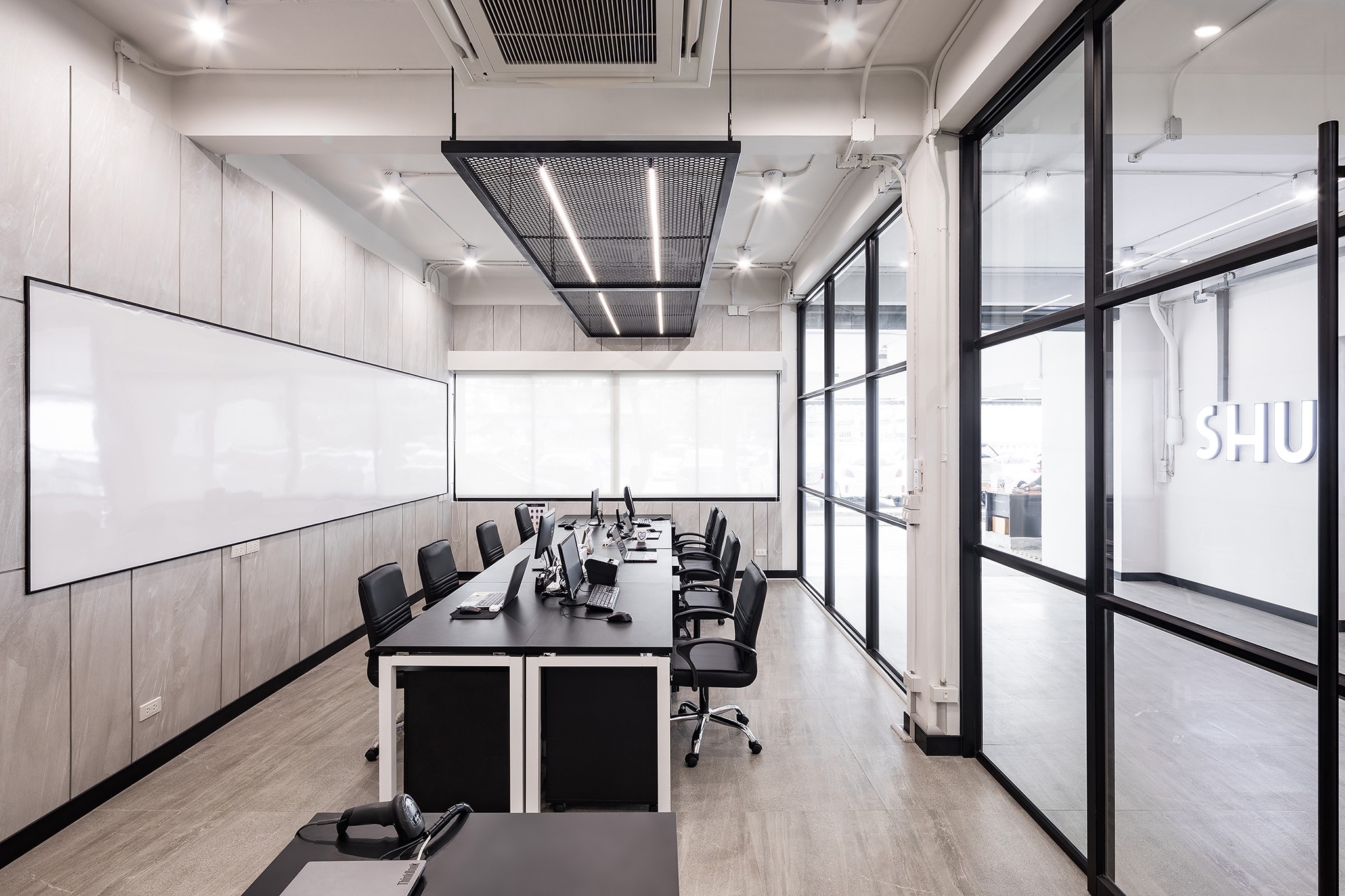 Workplace interior design in Bangkok — shared bench desking against a full-length whiteboard wall