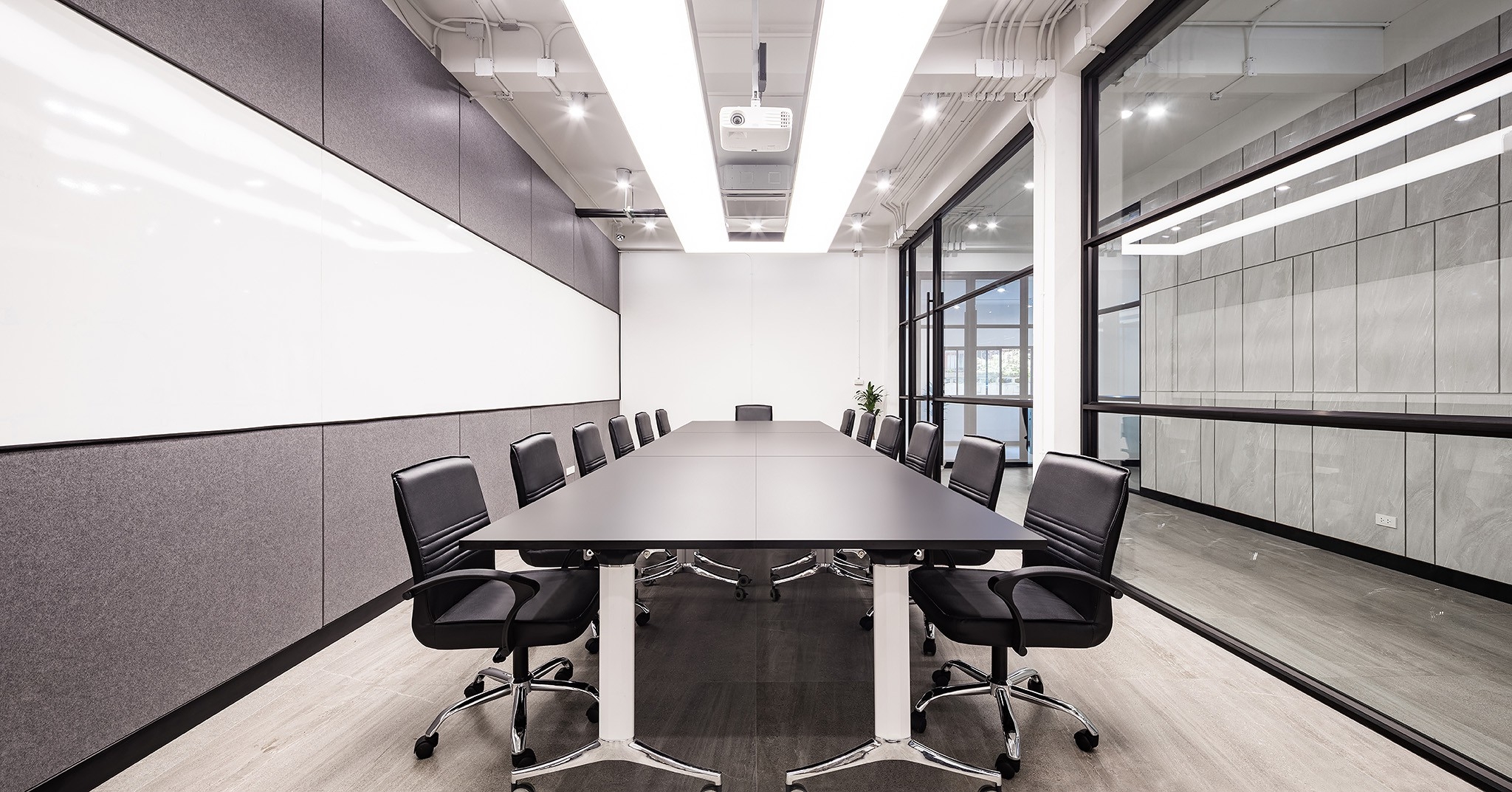 Meeting room interior design in Bangkok — acoustic felt wall and linear cove lighting over a twelve-seat table