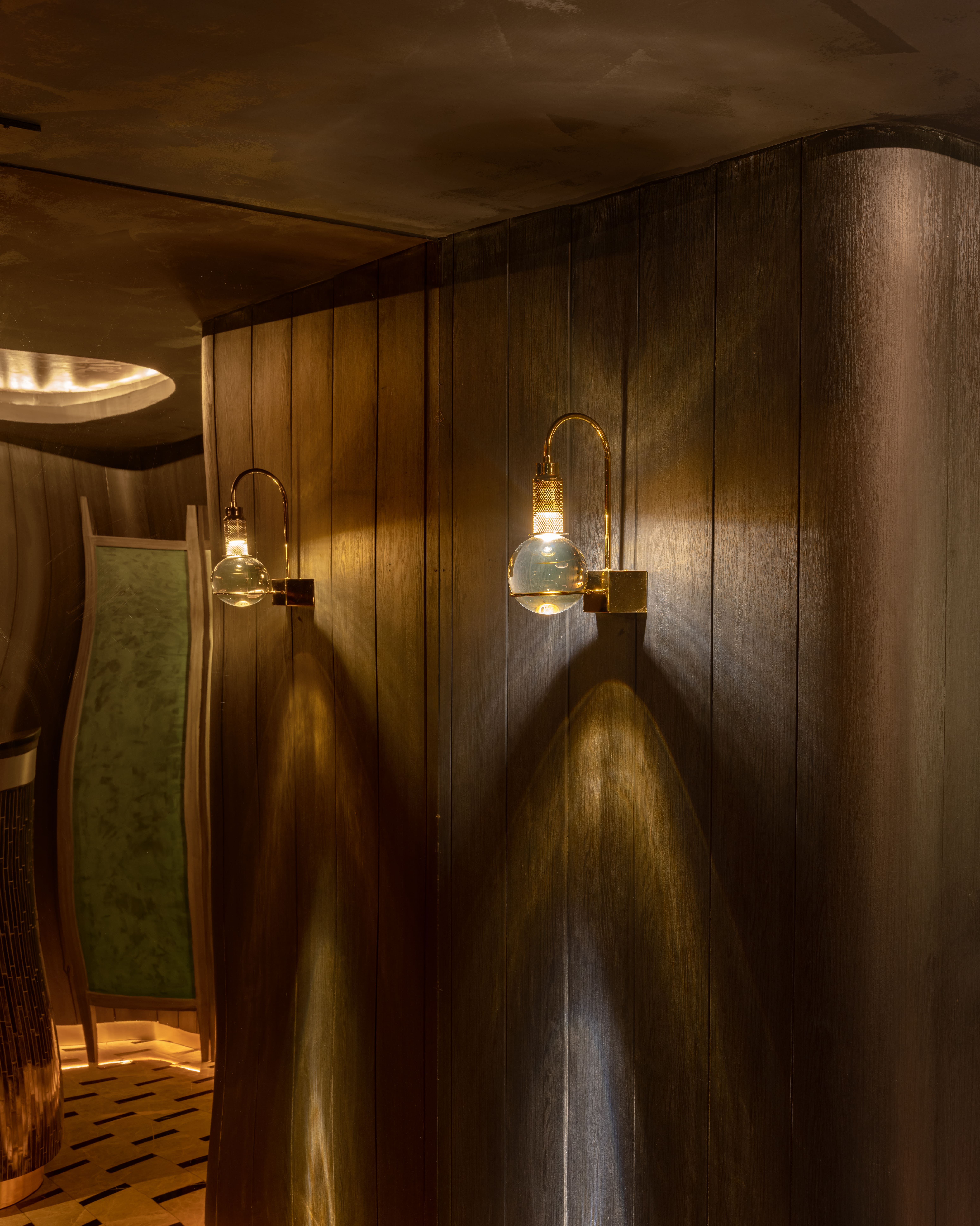 Timber panelling with paired glass wall lamps