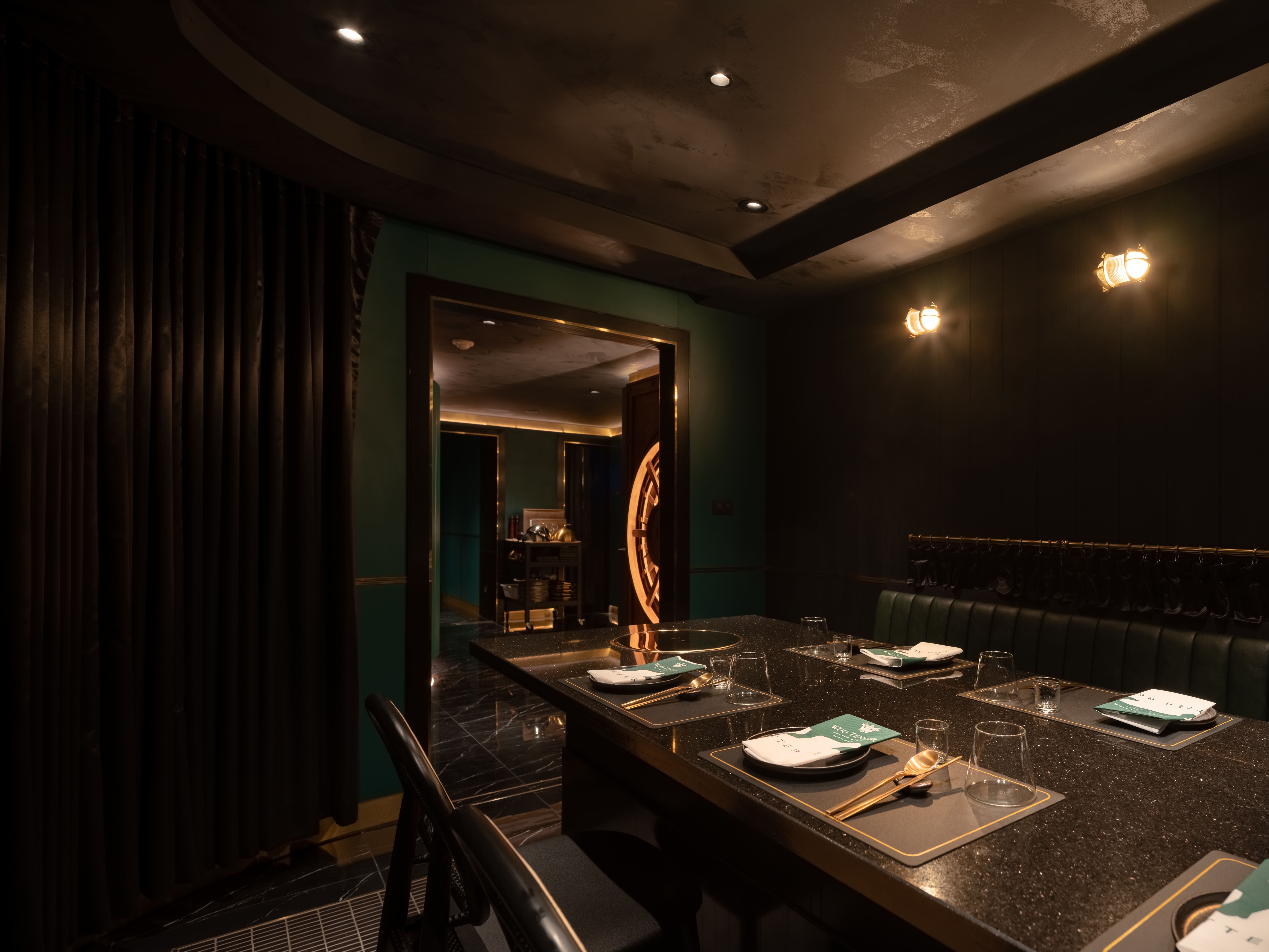 Private dining room at Woo Tender lined in deep green and lit only at the table