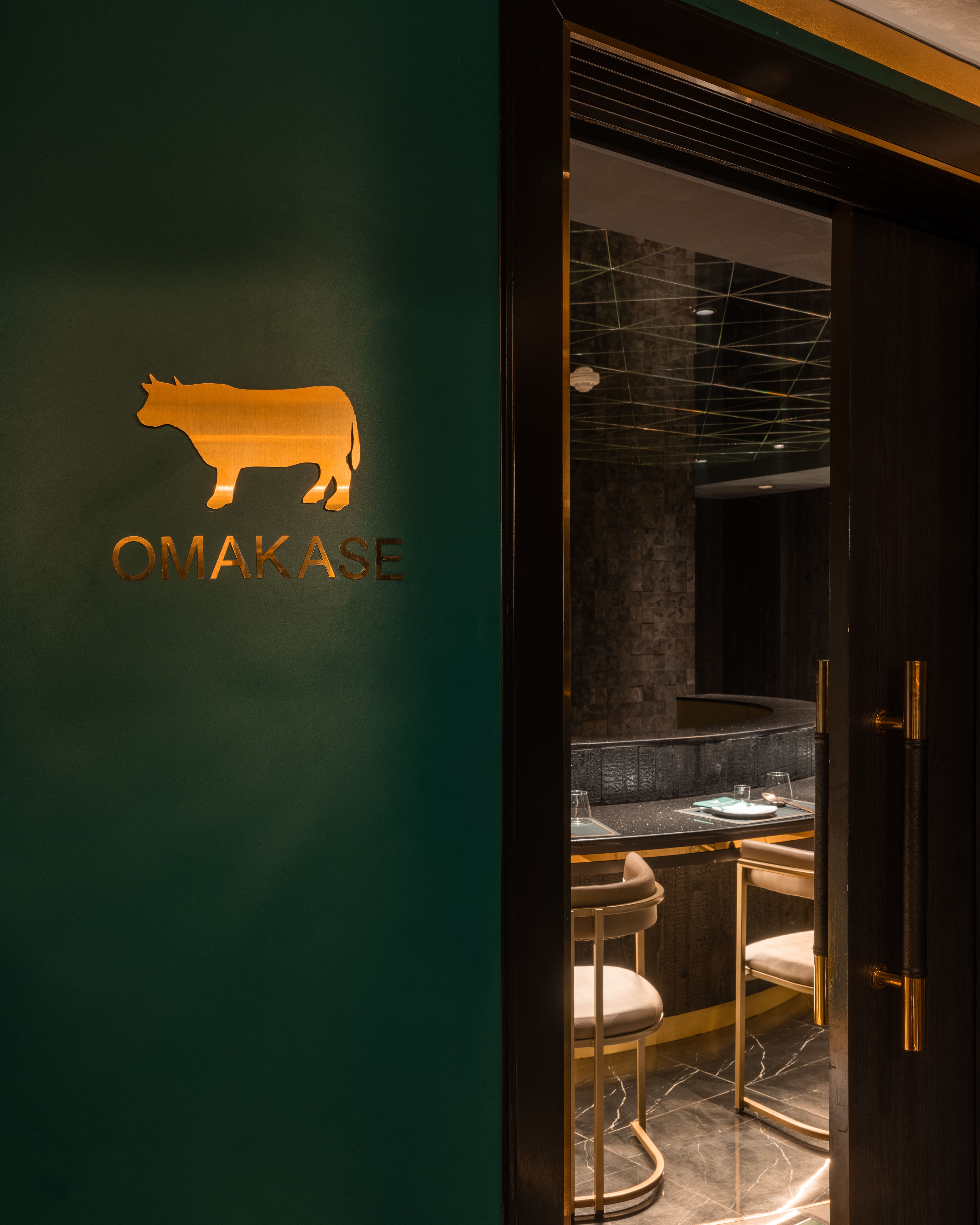 Gold bull emblem marking the omakase threshold on a green wall