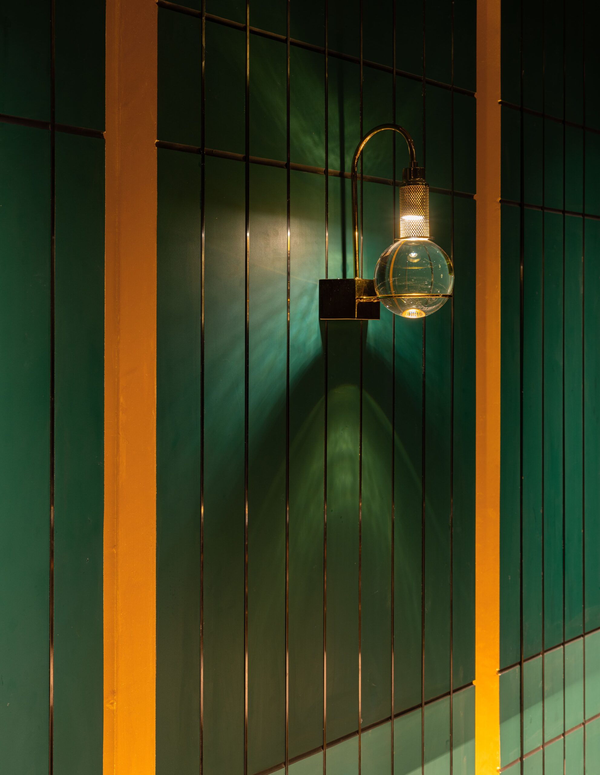 Green fluted panel with a gold reveal and a glass wall lamp