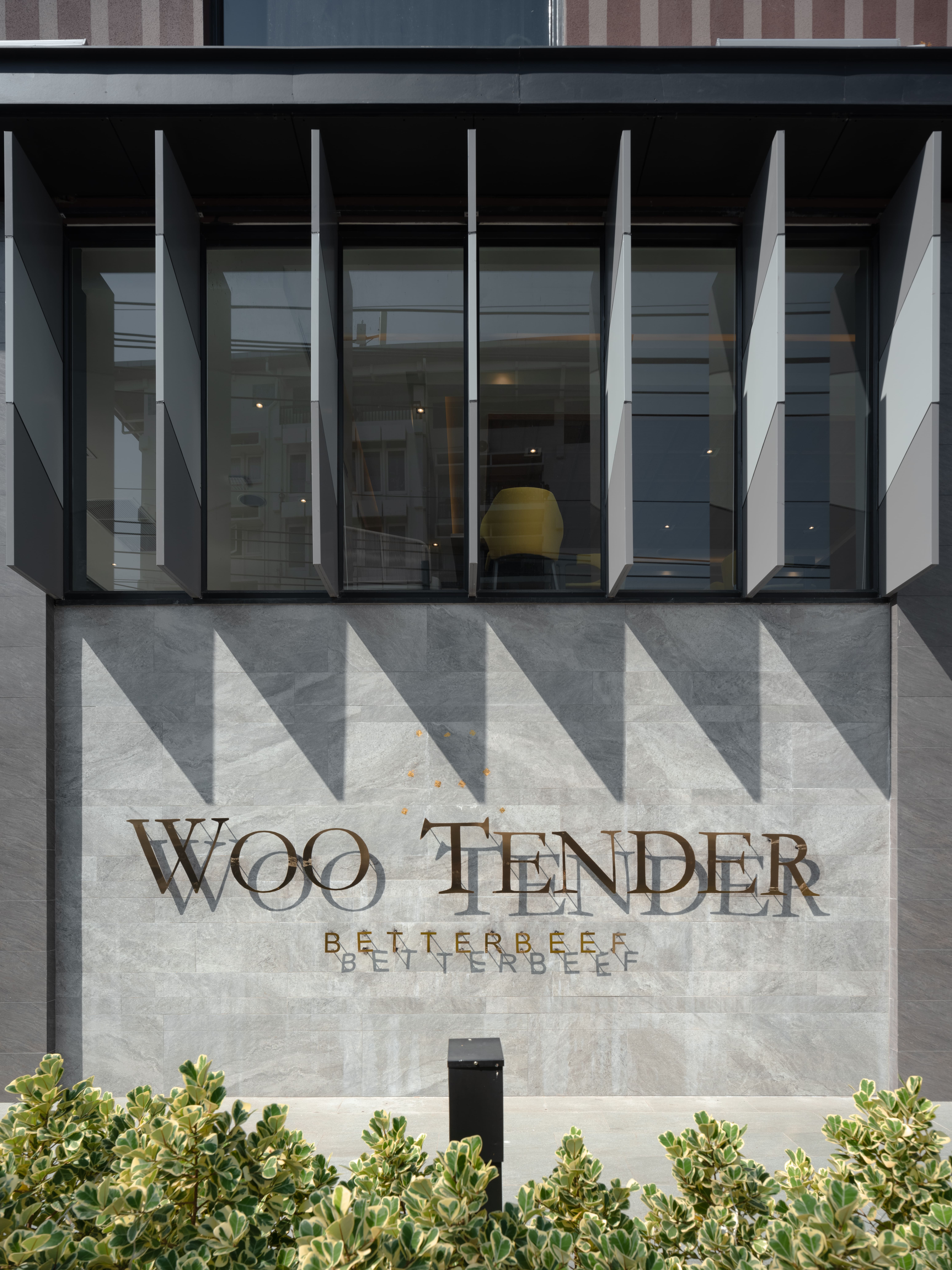 Woo Tender signage in gold on the marble frontage