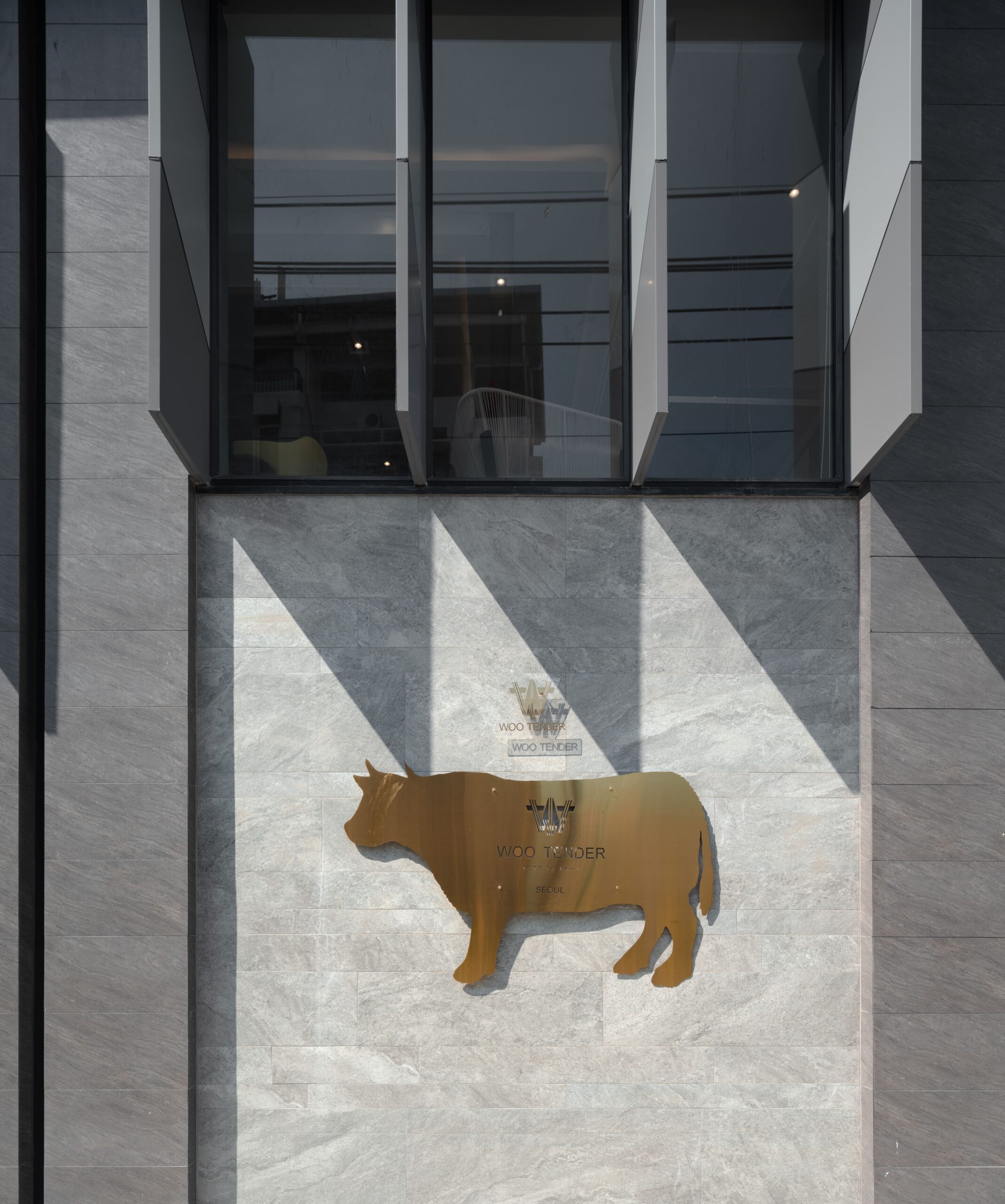 Woo Tender exterior in pale marble with a gold bull emblem