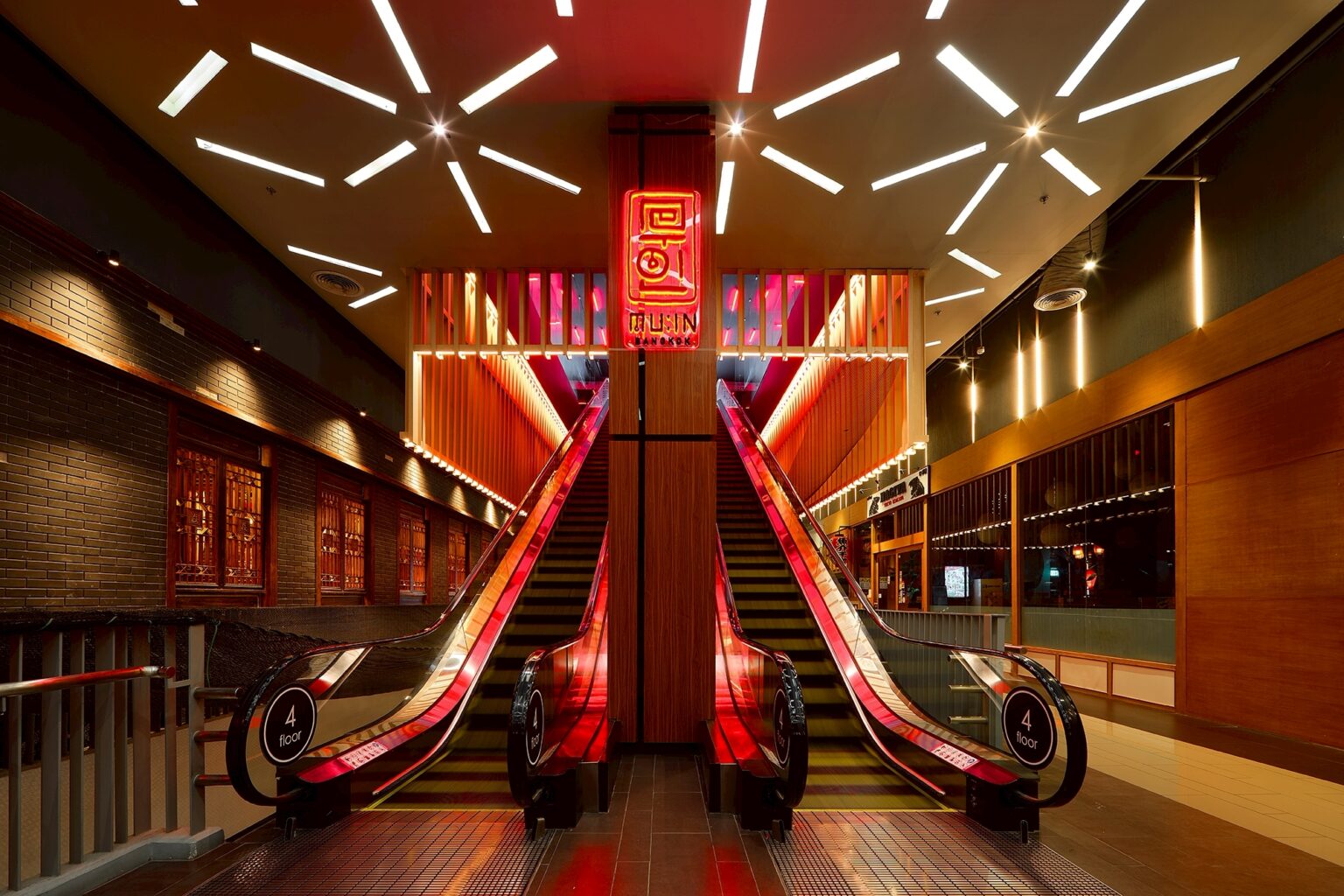 MU:IN Bangkok nightclub interior design — Arrival — twin escalators rise through a graphic ceiling of light