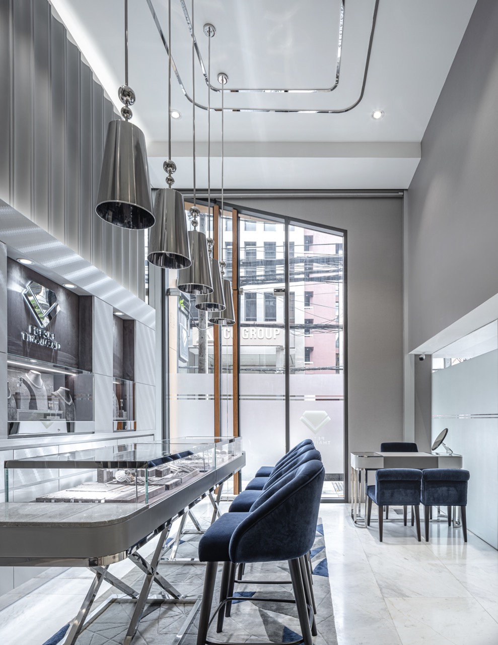 Seated diamond comparison counter beneath polished chrome pendants at the shopfront window