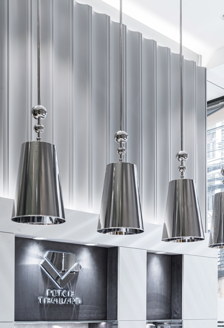 Fluted feature wall lit by polished chrome pendant lights in an engagement ring store interior