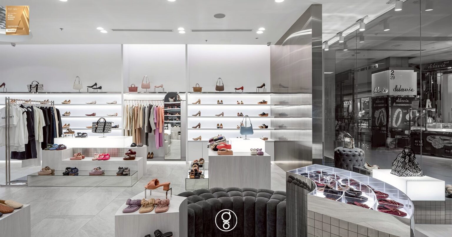 Curved mosaic display island with a lit acrylic grid top, velvet seating and backlit shelving beyond in the SHU store
