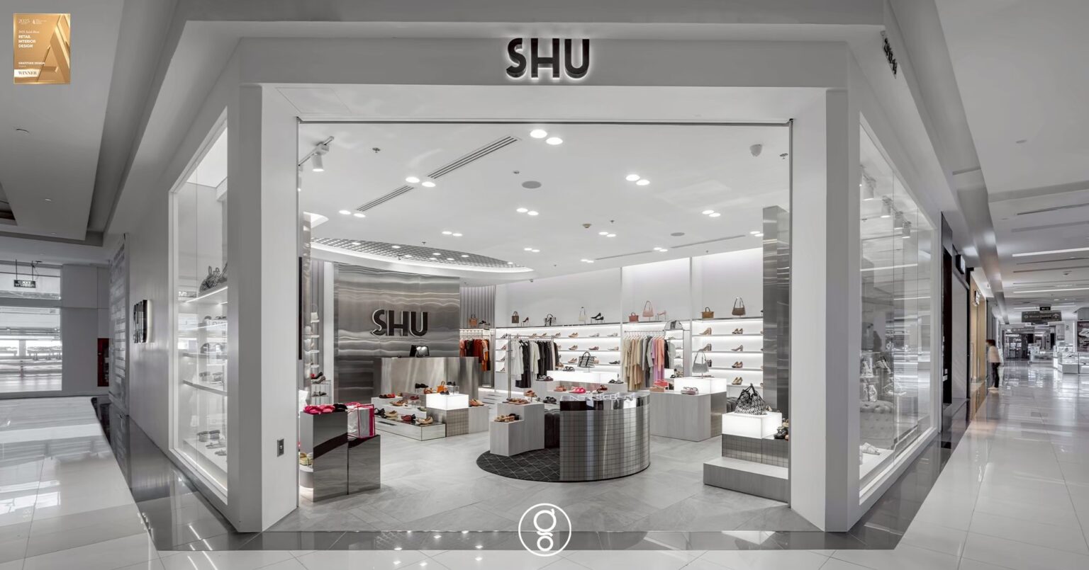 SHU shopfront seen from the mall concourse at Fashion Island, a full-glass frontage under black dimensional lettering