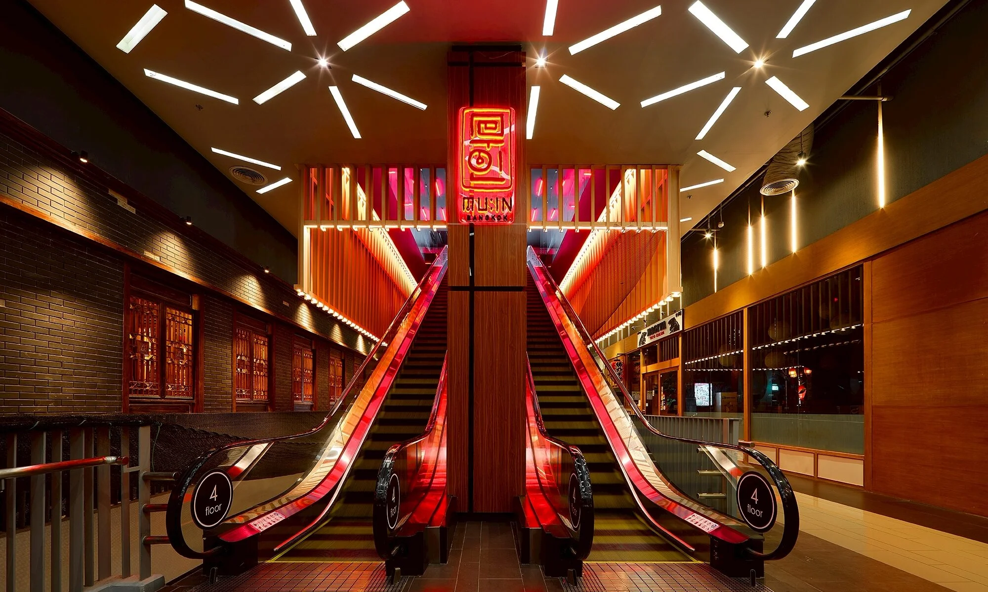 Twin escalators rising beneath an illuminated graphic ceiling at MU:IN nightclub in Thonglor, Bangkok
