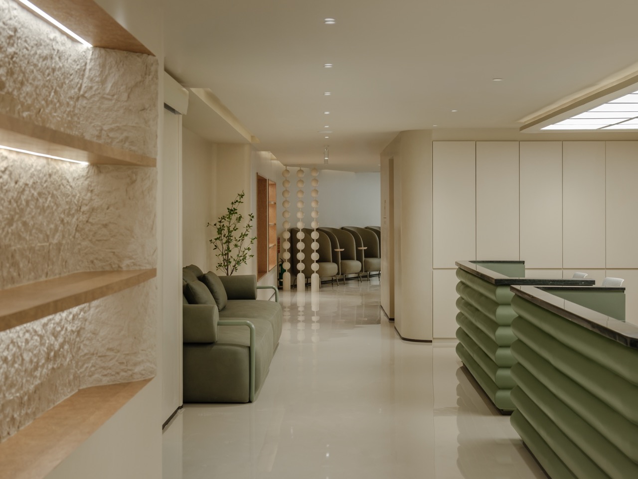 ทางเดิน Hairtran Clinic — ผนังหินผิวเทกซ์เจอร์พร้อมชั้นไม้ซ่อนไฟ โซฟาสีเขียว ม่านลูกปัด และเคาน์เตอร์ต้อนรับ